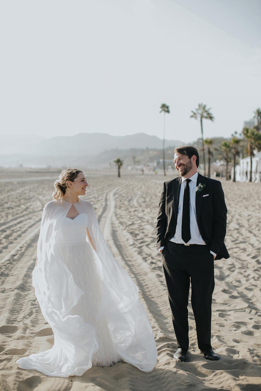 bridal cape and feathered wedding dress and black groom suit