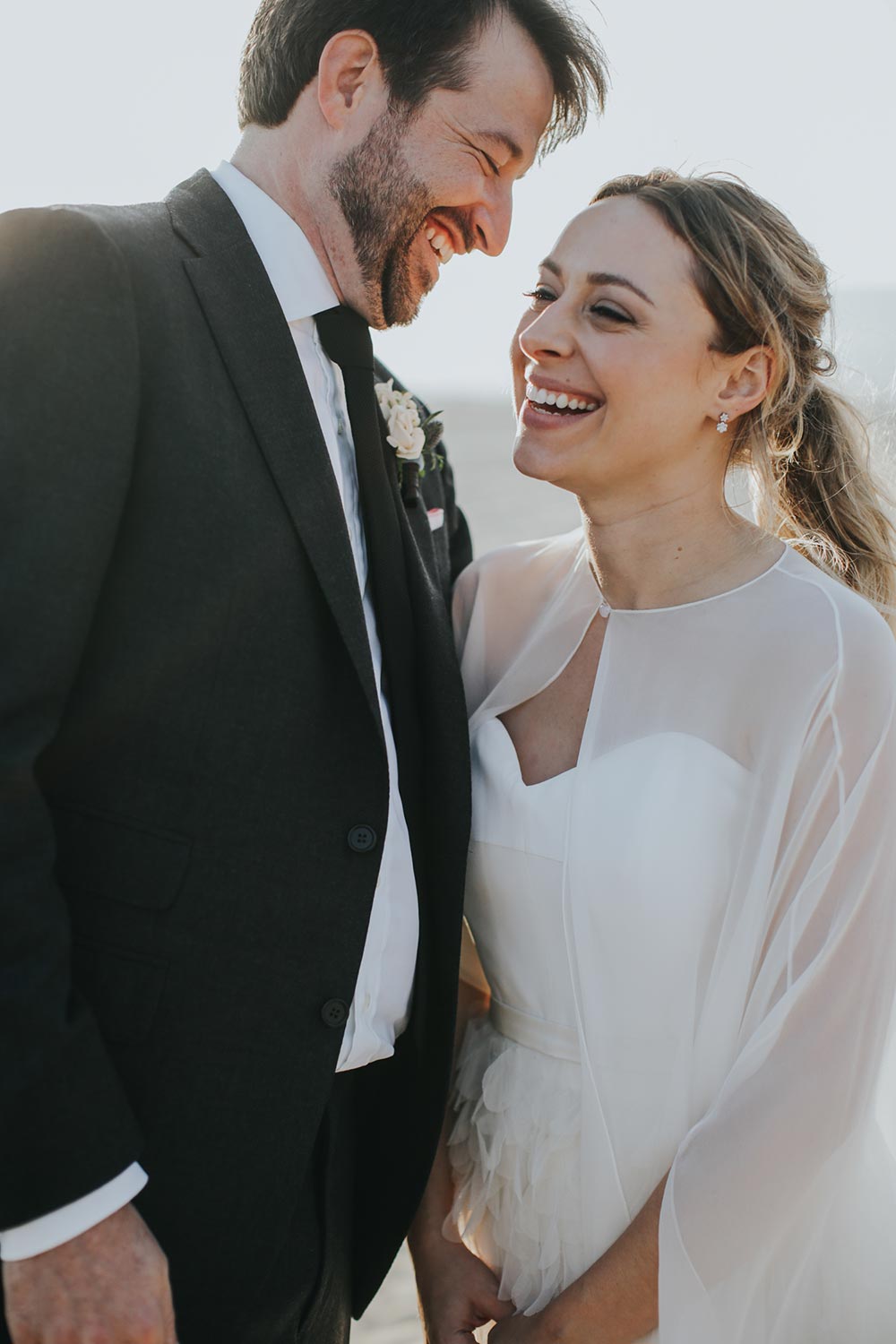 bridal cape and feathered wedding dress and black groom suit