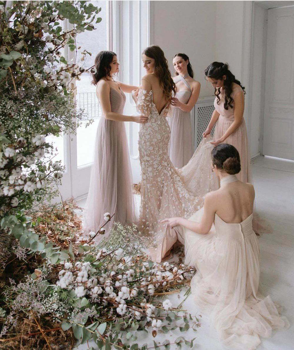 bridesmaids helping bride into wedding dress